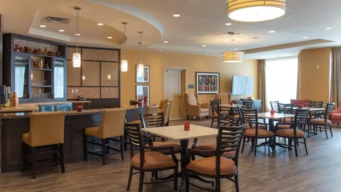 Bar and seating area with tables, chairs, a television and patterned tile