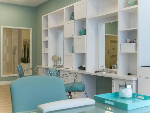 Salon with turquoise chairs, wall mirrors and white shelving