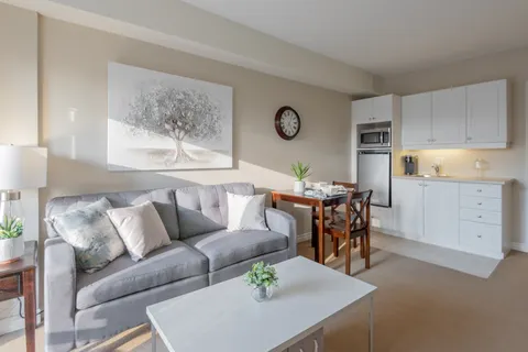 Sofa and dining table beside a kitchenette with white cabinets