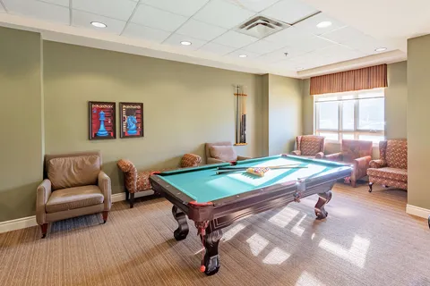 Billiard table and armchairs beneath chess-piece posters