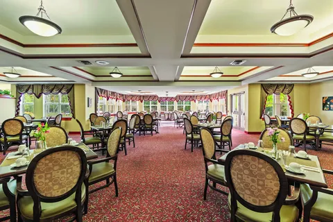Dining room with round-backed chairs, set tables and large windows