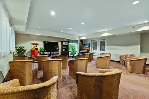 Room with rows of upholstered chairs facing a dark television