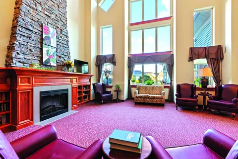 High-ceilinged seating area with a stone fireplace, tall windows and purple armchairs
