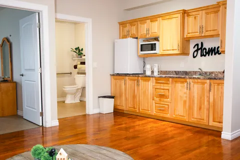 Suite kitchenette with wooden cupboards beside a bathroom doorway.