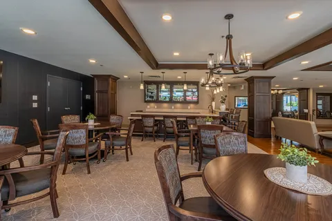 Room with round tables, chairs, a counter, glass cabinets and hanging lights