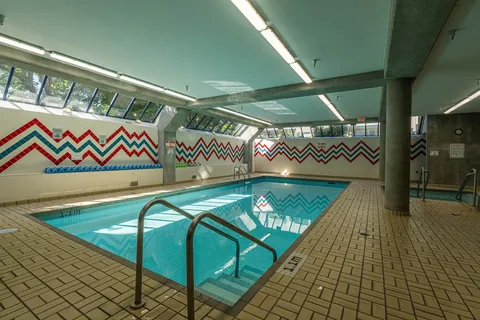 Indoor swimming pool with metal handrails, concrete columns and patterned wall tiles