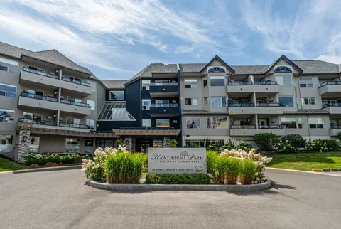 Four-storey residence with balconies, a covered entrance and flower beds around a driveway