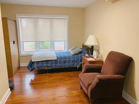 Bedroom with a bed, upholstered chair and window.