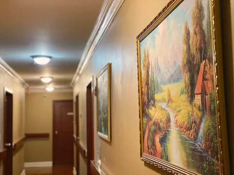 Corridor with framed paintings and ceiling lights.