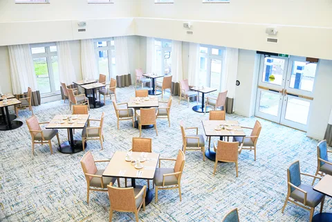 Dining room with set tables, woven chairs and tall windows