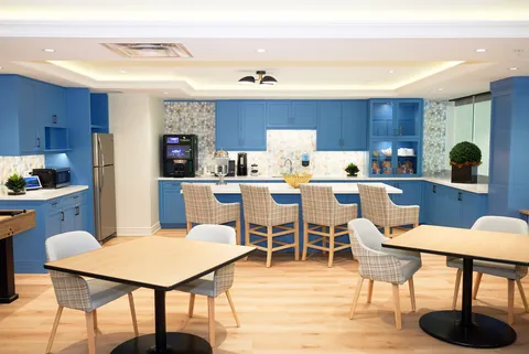 Room with tables, counter stools, blue cabinets and beverage machines