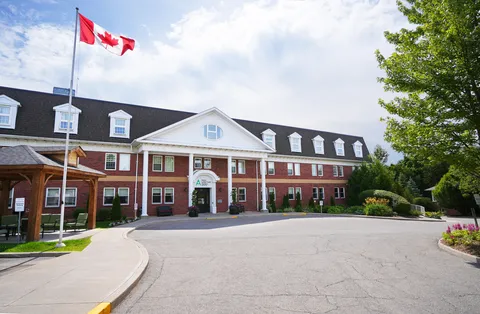 Three-storey red-brick building with white columns, a curved driveway and a Canadian flag