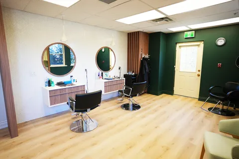 Salon with styling chairs, round mirrors and wooden stations