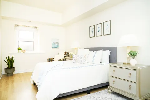 Bedroom with a white-covered bed, bedside tables and botanical artwork