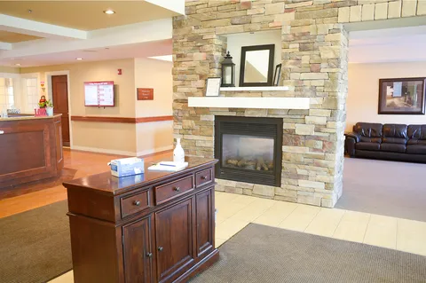 Reception area with a stone fireplace, wooden counter, black sofas and a mirror