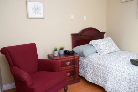 Bedroom with a patterned bedspread, red armchair and wooden nightstand