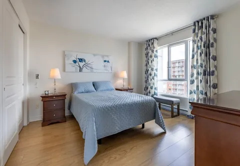 Bedroom with a blue bedspread, floral wall art and a large window