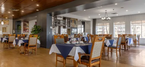 Dining room with wooden chairs and tables covered with white cloths