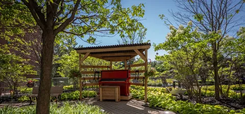 Red upright piano beneath a wooden pergola in a garden