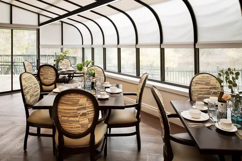 Dining tables beside curved conservatory windows