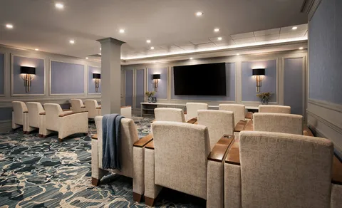 Cinema lounge with armchairs facing a large screen