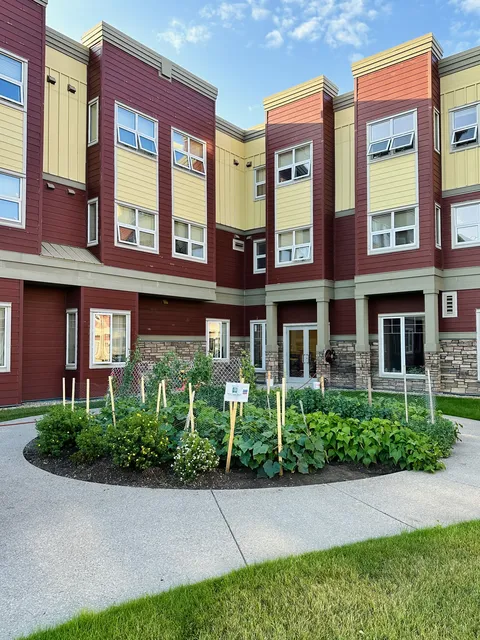 Multi-storey building with red and yellow siding beside a planted courtyard