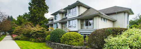 Residence building with balconies, shrubs and a sidewalk