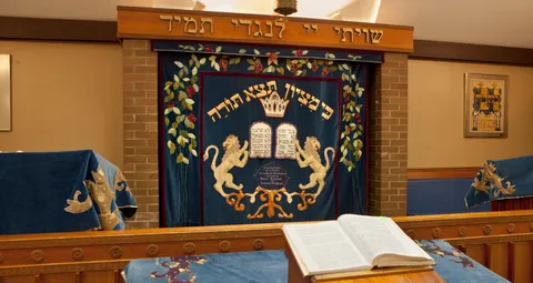 Synagogue ark with an embroidered curtain and an open book on a wooden lectern