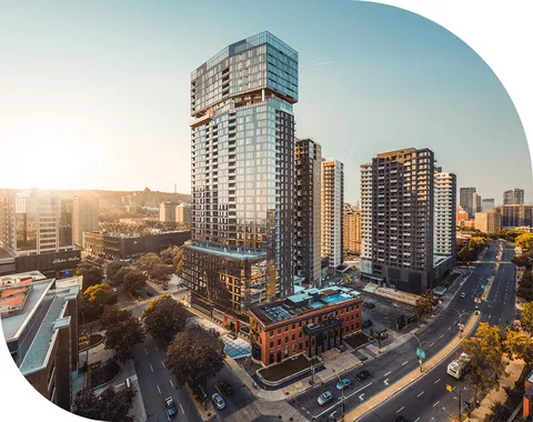 Aerial view of a glass residential tower and neighbouring buildings.