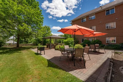 Garden patio with umbrellas, tables and paths beside the residence.