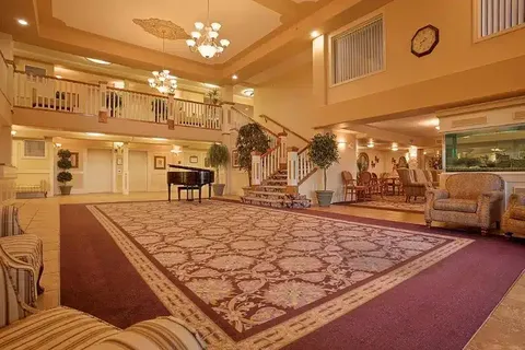 Lobby with a piano, staircase, armchairs and an upper balcony