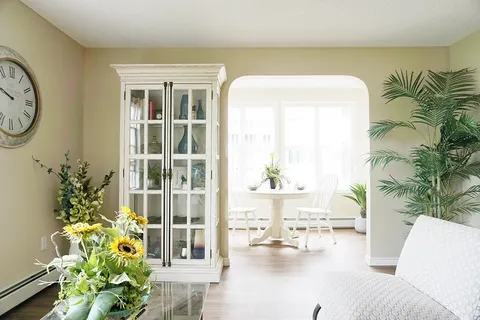 Sitting area with a glass-front cabinet and an adjoining table beside large windows