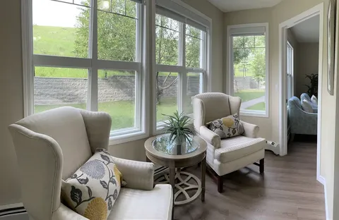 Windowed sitting area with two cream armchairs and a round table