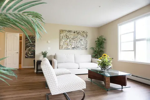 Sitting area with a white sofa, two chairs, coffee table and abstract artwork
