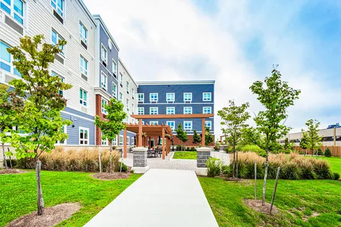 Path through landscaped lawns toward a patio beside the building