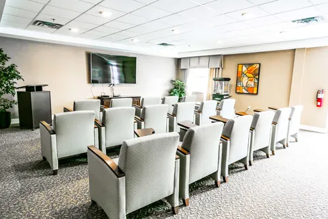 Rows of upholstered seats facing a dark television screen