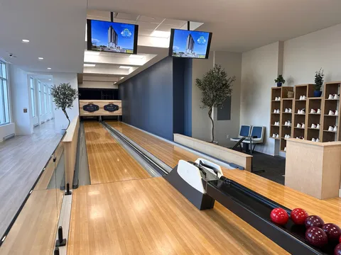Empty bowling lanes with balls, scoring screens and shoe shelves.