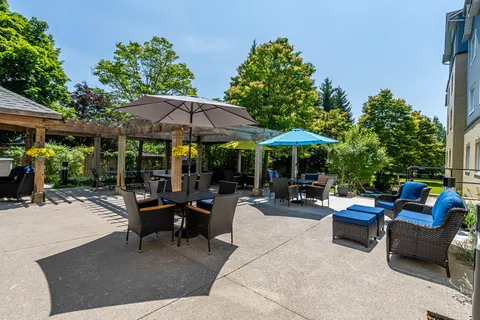 Patio with a wooden pergola, umbrellas, tables and blue cushioned chairs