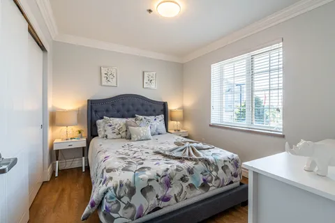 Bedroom with a floral bedspread, bedside lamps and a window