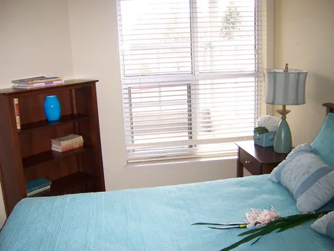 Bedroom with a blue bedspread and a window.