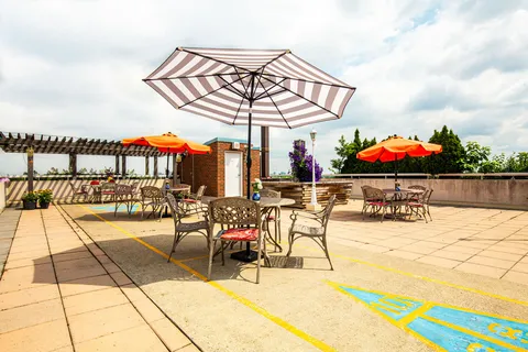 Rooftop patio tables and chairs beneath striped and orange umbrellas