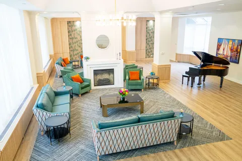 Sofas and armchairs around a fireplace beside a grand piano