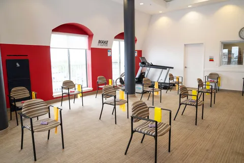 Chairs arranged around exercise equipment in a room with red window recesses