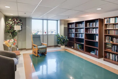 Library with armchairs, bookshelves and a large window