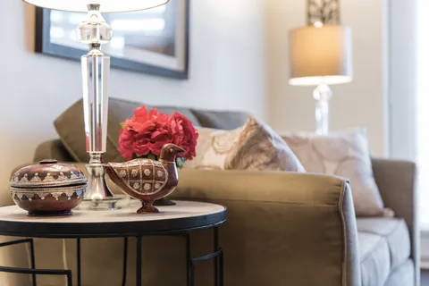 Side table with a lamp, a lidded pot and a bird ornament beside a sofa