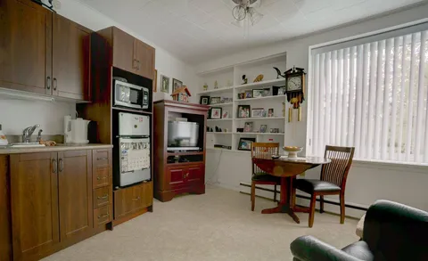 Kitchenette with a refrigerator, sink and dining table.