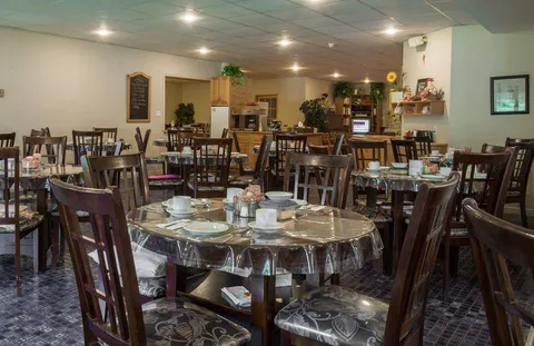 Dining room with tables and chairs beside large windows.