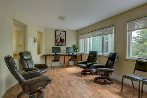 Lounge with leather armchairs and two computer stations.