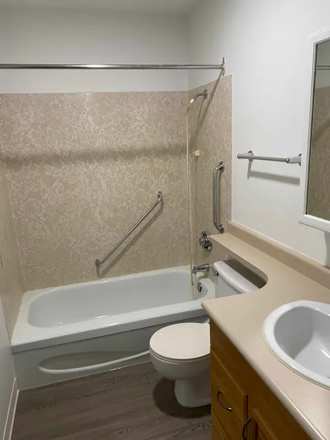 Bathroom with a bathtub, toilet, sink and grab bars