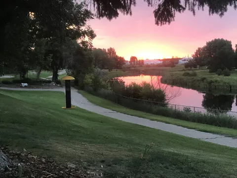 Garden path beside a pond, lawn and trees at sunset